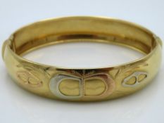 An 18ct three colour gold bangle, 25.1g, with plus