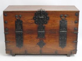 An Oriental oak chest with drop down front and iro