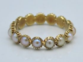 A yellow metal eternity ring set with pearl, tests