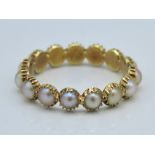 A yellow metal eternity ring set with pearl, tests