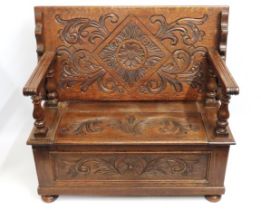 A carved oak monks bench with storage under seat, 1070mm wide x 540mm deep x 750mm high (when closed