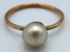 A yellow metal ring set with pearl, tests electron