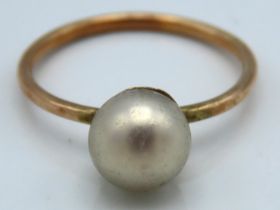 A yellow metal ring set with pearl, tests electron