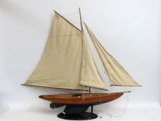 A large wooden model of a yacht & stand, 1195mm tall x 995mm long
