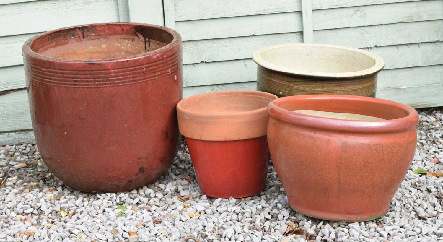Three red glazed terracotta garden planters and a brown glazed example