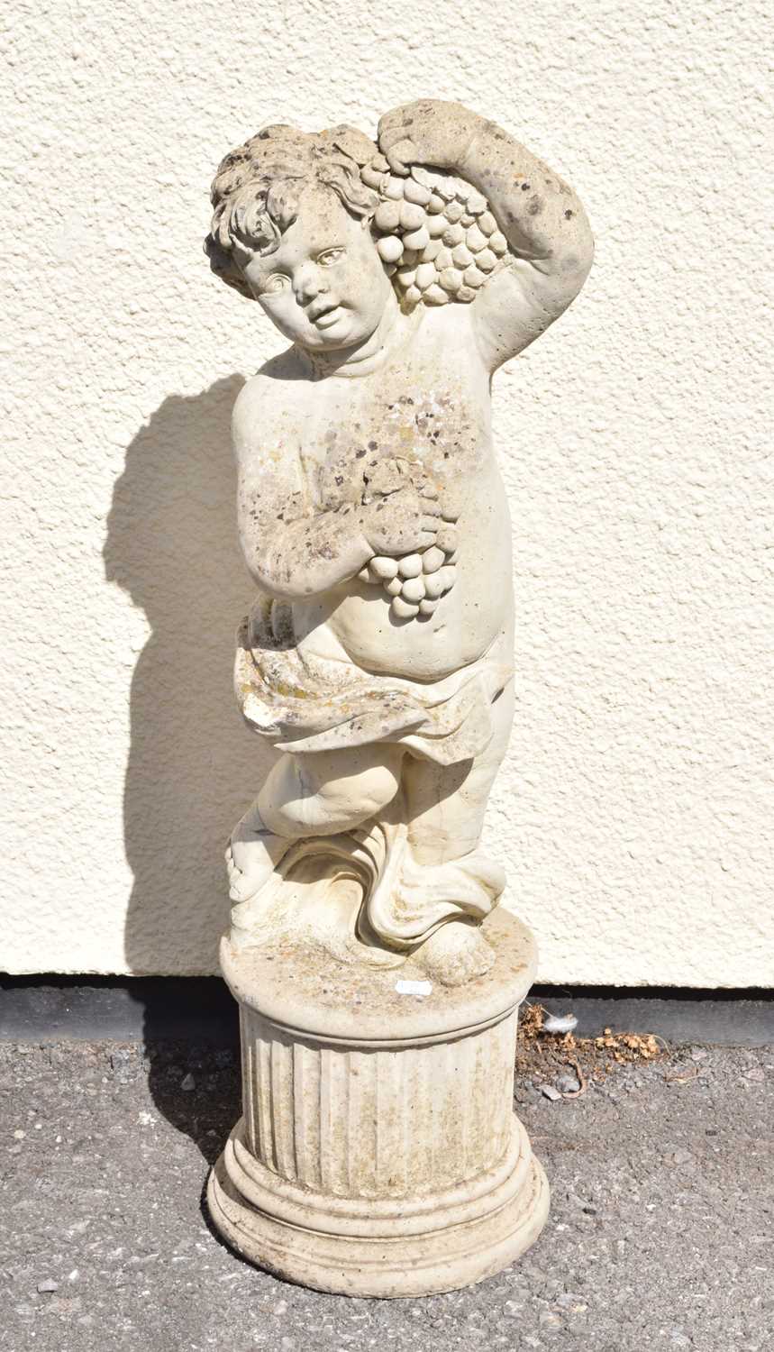 Composite stone garden statue of a cherub holding grapes