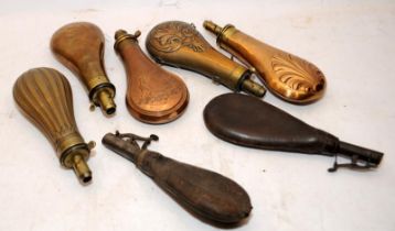 A collection of antique powder flasks. Copper/brass and leather examples. 7 in lot