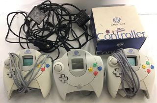 SEGA DREAMCAST CONTROLLERS. A total of 3 hand held devices here with a collection of Rf converter