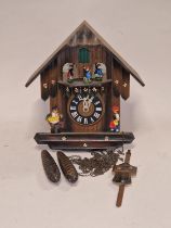 A black forest style wooden cuckoo clock with weights and pendulum.