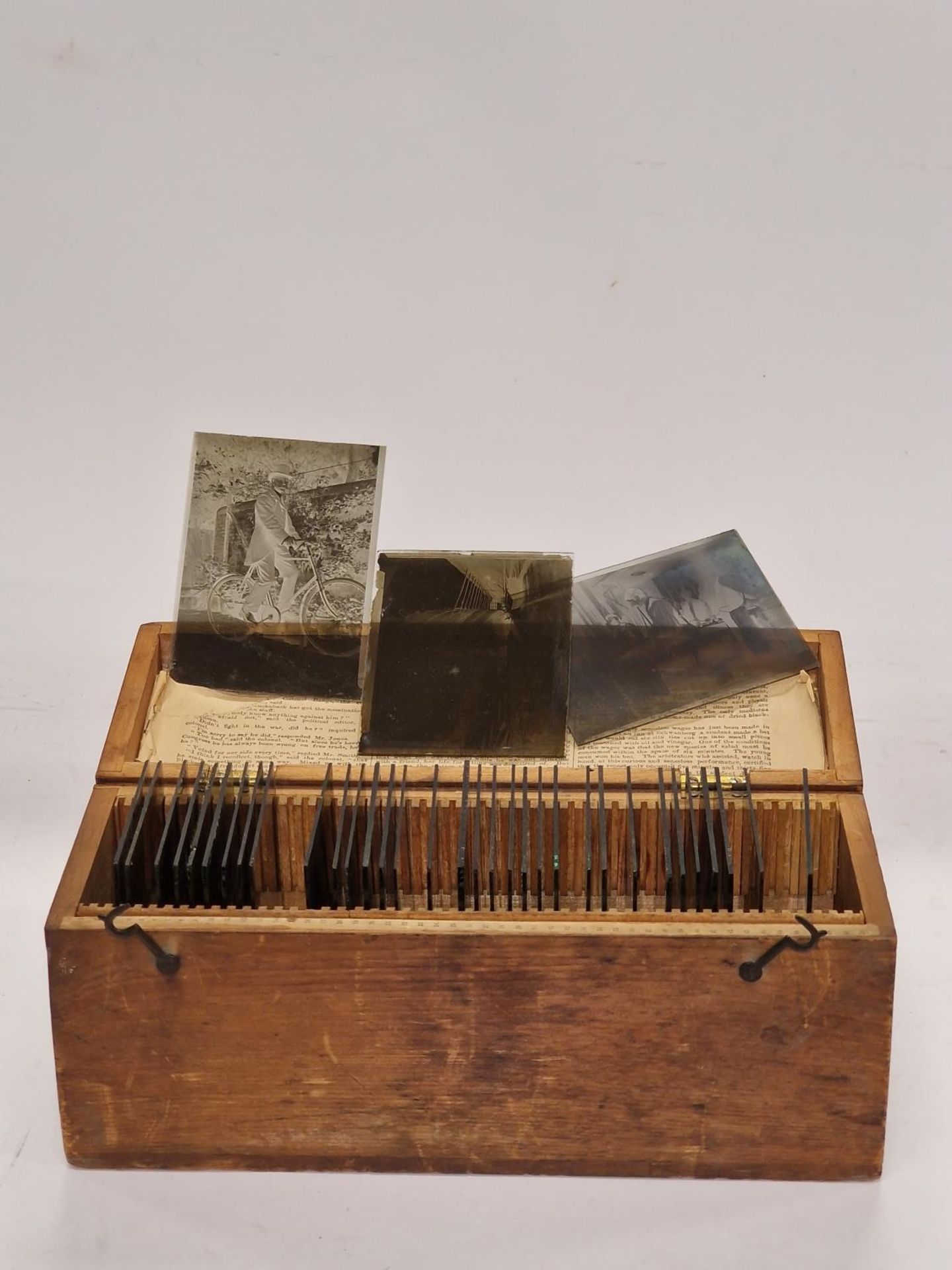 A wooden box containing a collection of antique glass slides. Various subjects.