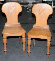 Pair of vintage oak hallway chairs with decorative shield backs.