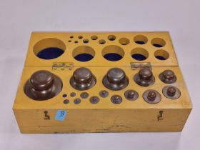 Wooden box containing a full set of vintage brass weights.