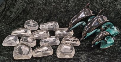 A collection of glass flat back animal paperweights together with three Poole Pottery dolphins.