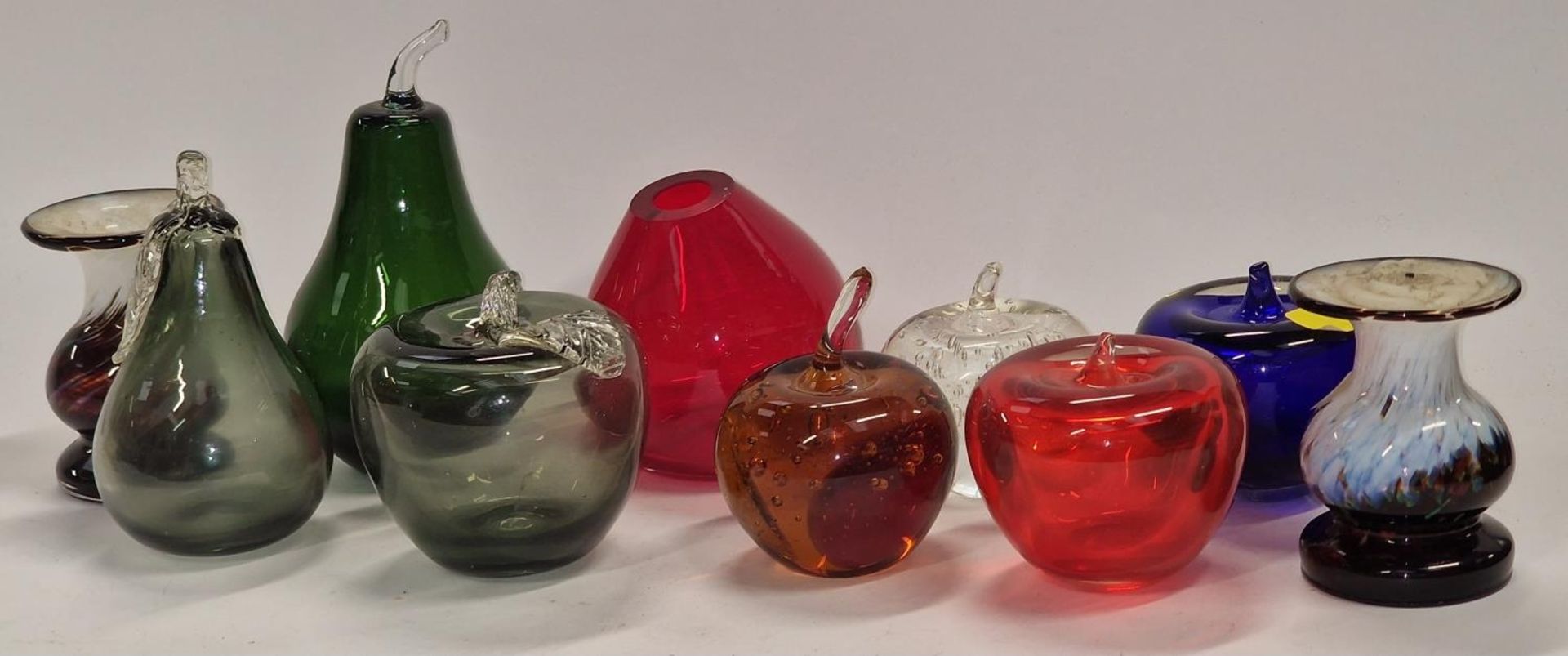A collection of coloured glass fruits together with a pair of glass candlesticks.