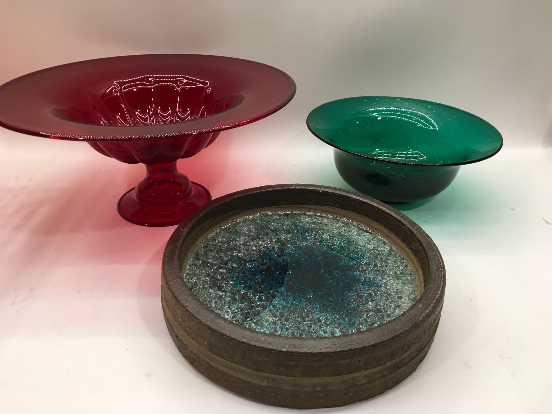 A cranberry glass centre piece together with a green glass bowl and one other.