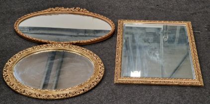 A collection of three vintage gilt framed mirrors two oval shaped and one square.