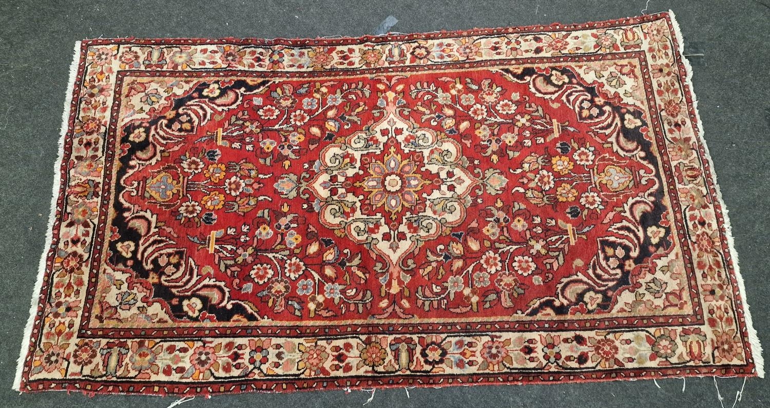 Large vintage patterned carpet on red ground 271x153cm.