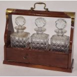 Vintage oak tantulus containing a matching set of three crystal glass decanters. Includes key.