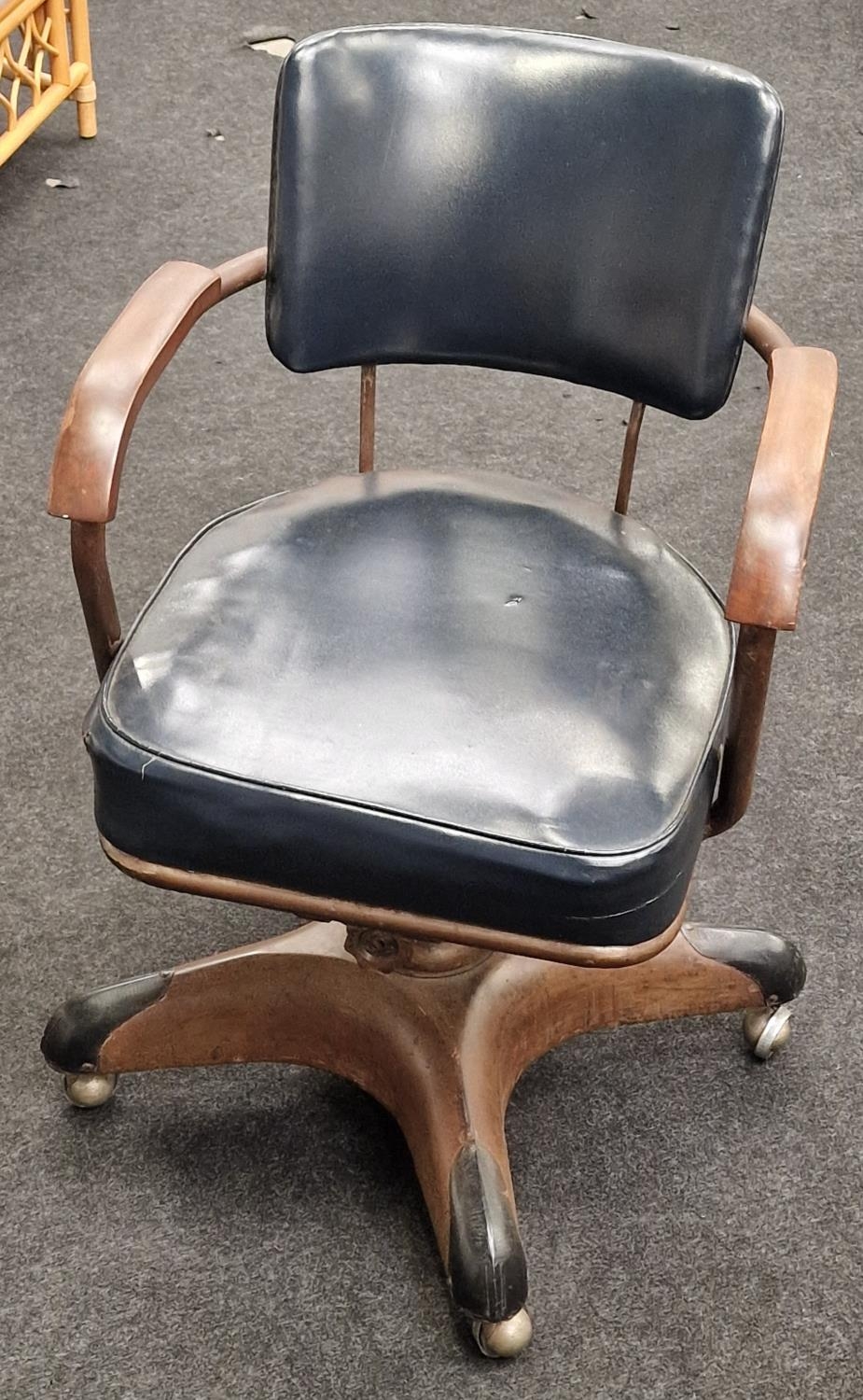 Revolving mid century office chair with cast metal base and casters, set on wooden arm rests