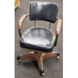 Revolving mid century office chair with cast metal base and casters, set on wooden arm rests