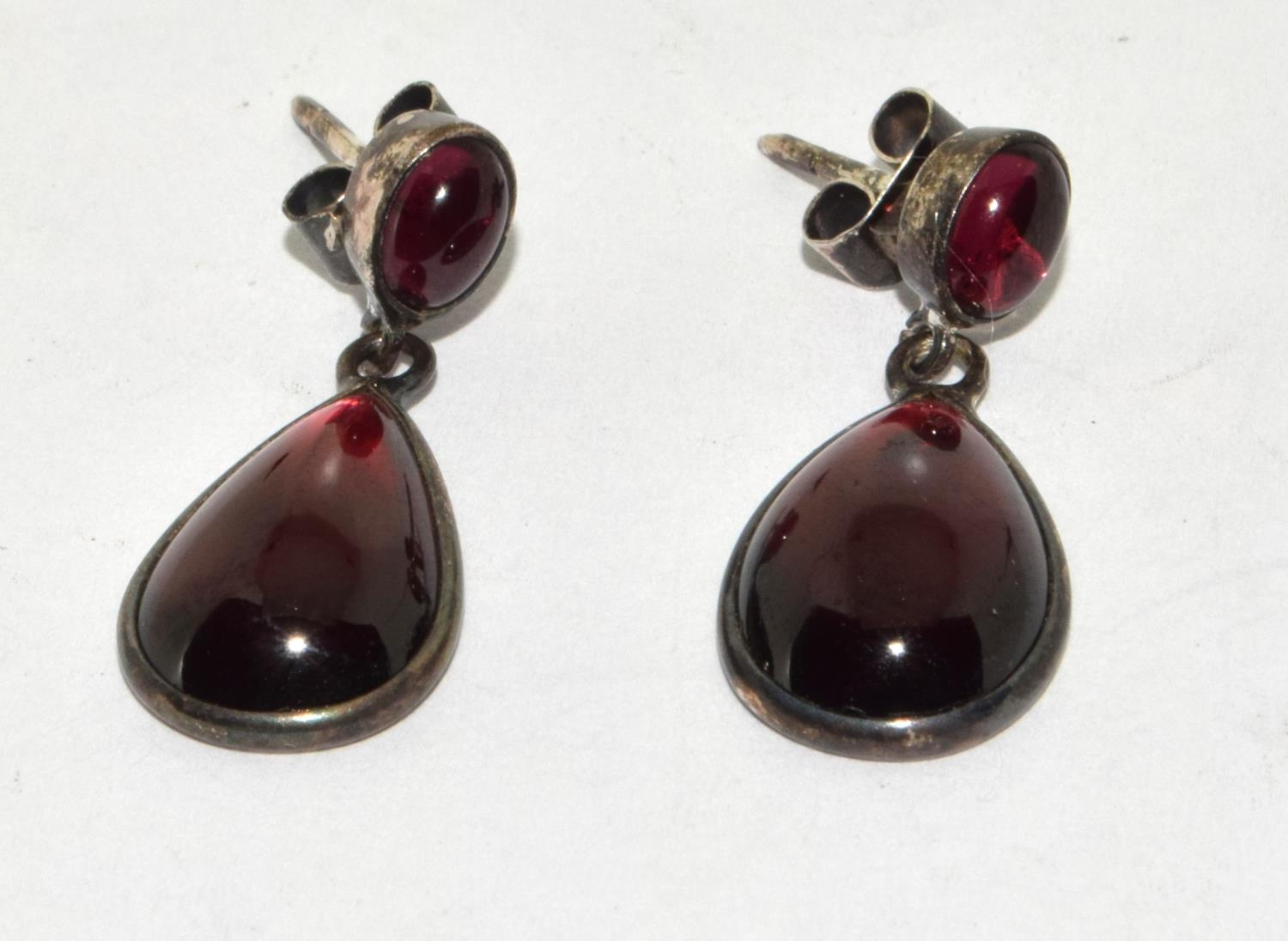Large natural cabochon pear shaped garnet and silver drop earrings.