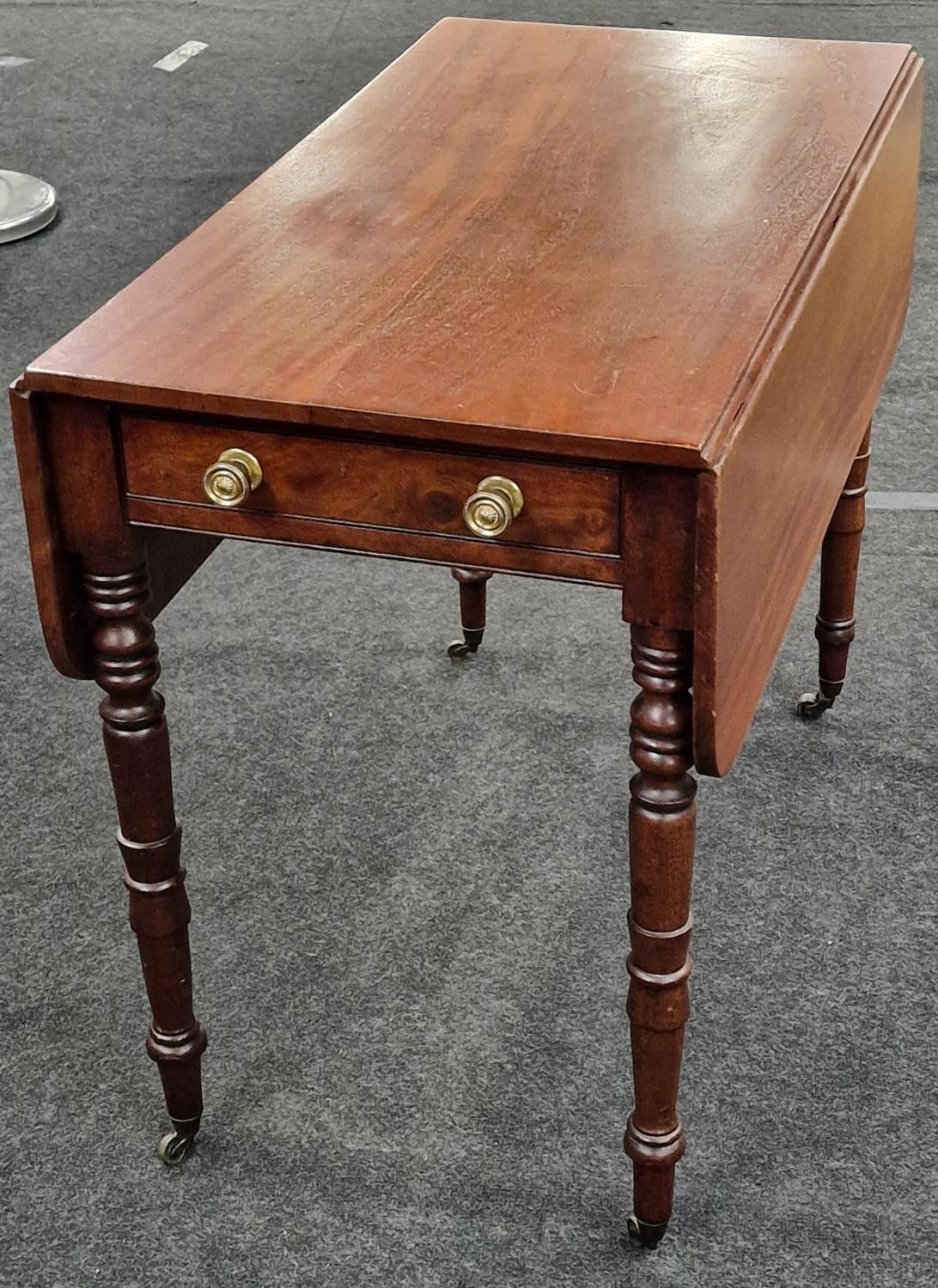 Mahogany Pembroke table supported by turned supports above brass castors having a single draw to one