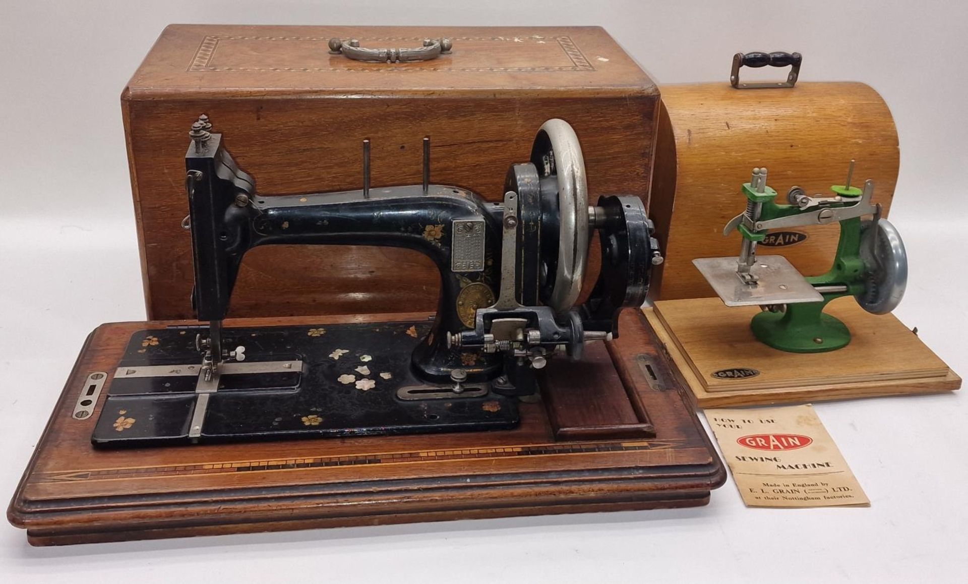 Vintage Grain miniature toy sewing machine together with a larger sewing machine.