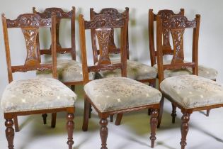 A set of six Victorian walnut dining chairs, with carved back and splats, raised on turned