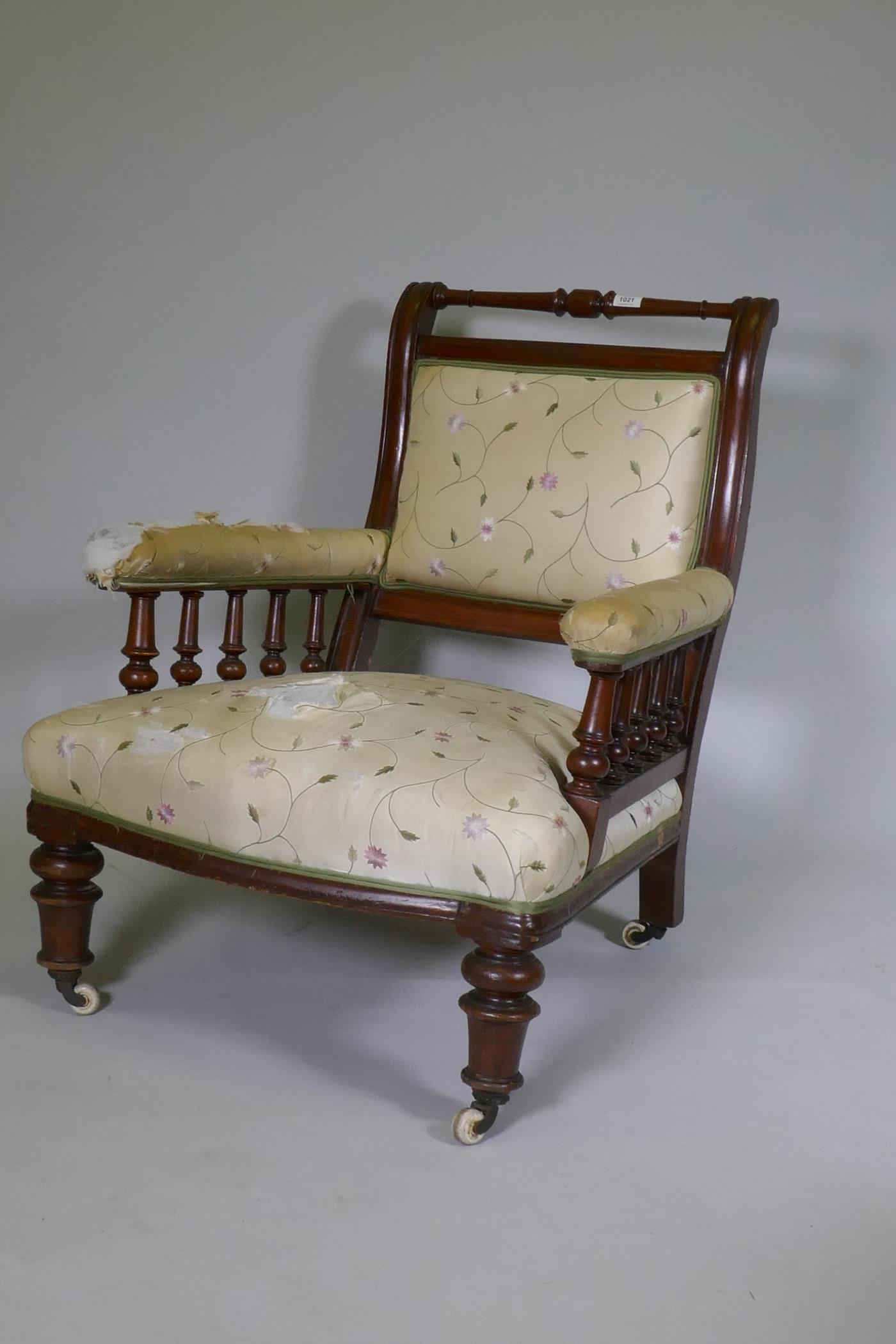 A Victorian walnut show frame easy chair, the open arms with turned spindles, raised on turned
