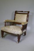A Victorian walnut show frame easy chair, the open arms with turned spindles, raised on turned