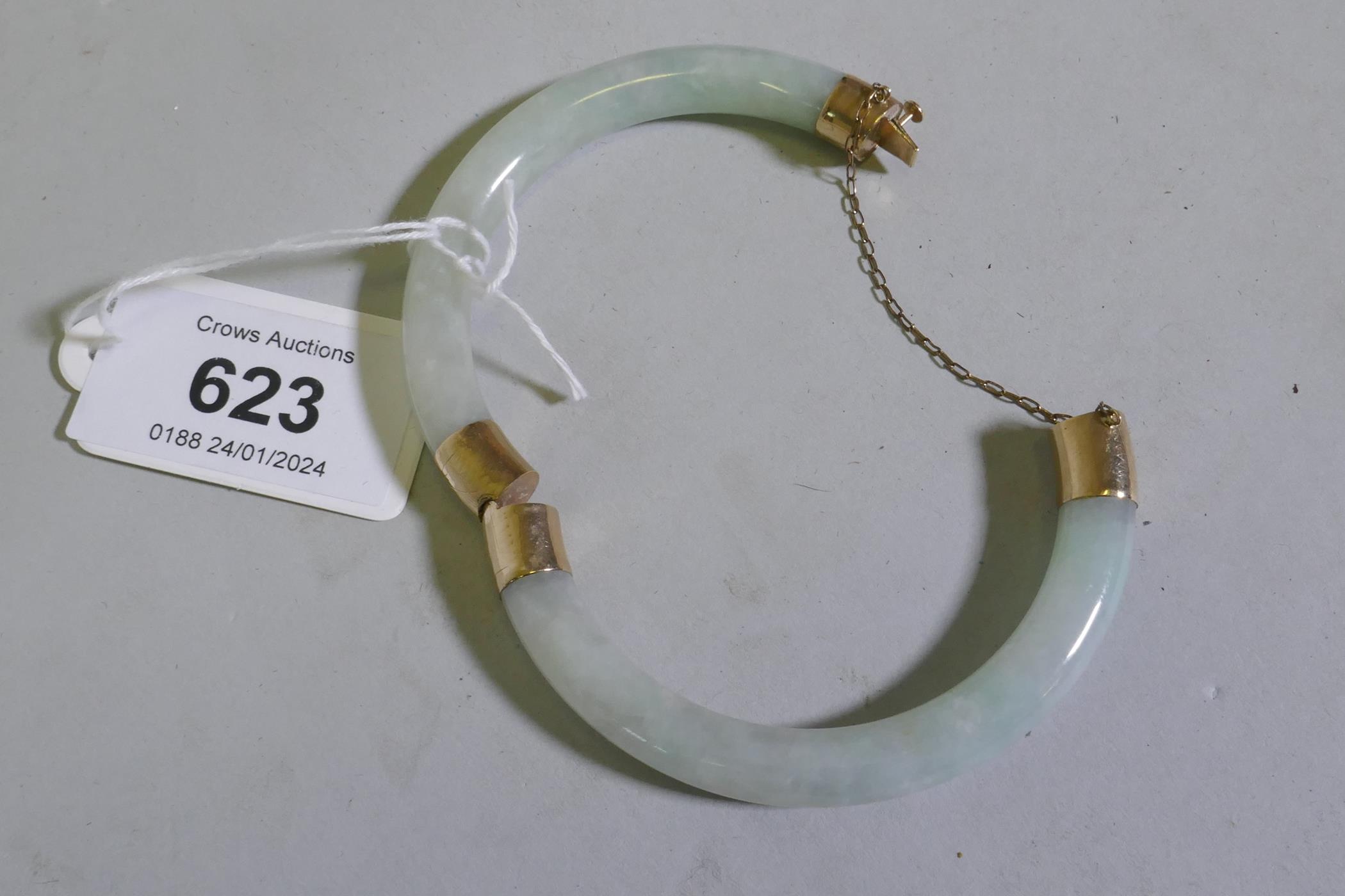 A jade bangle with 9ct gold mounts, 5.5cm internal diameter