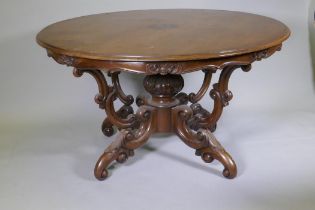 A C19th walnut centre table raised on carved baluster shaped columns and four scrolling supports