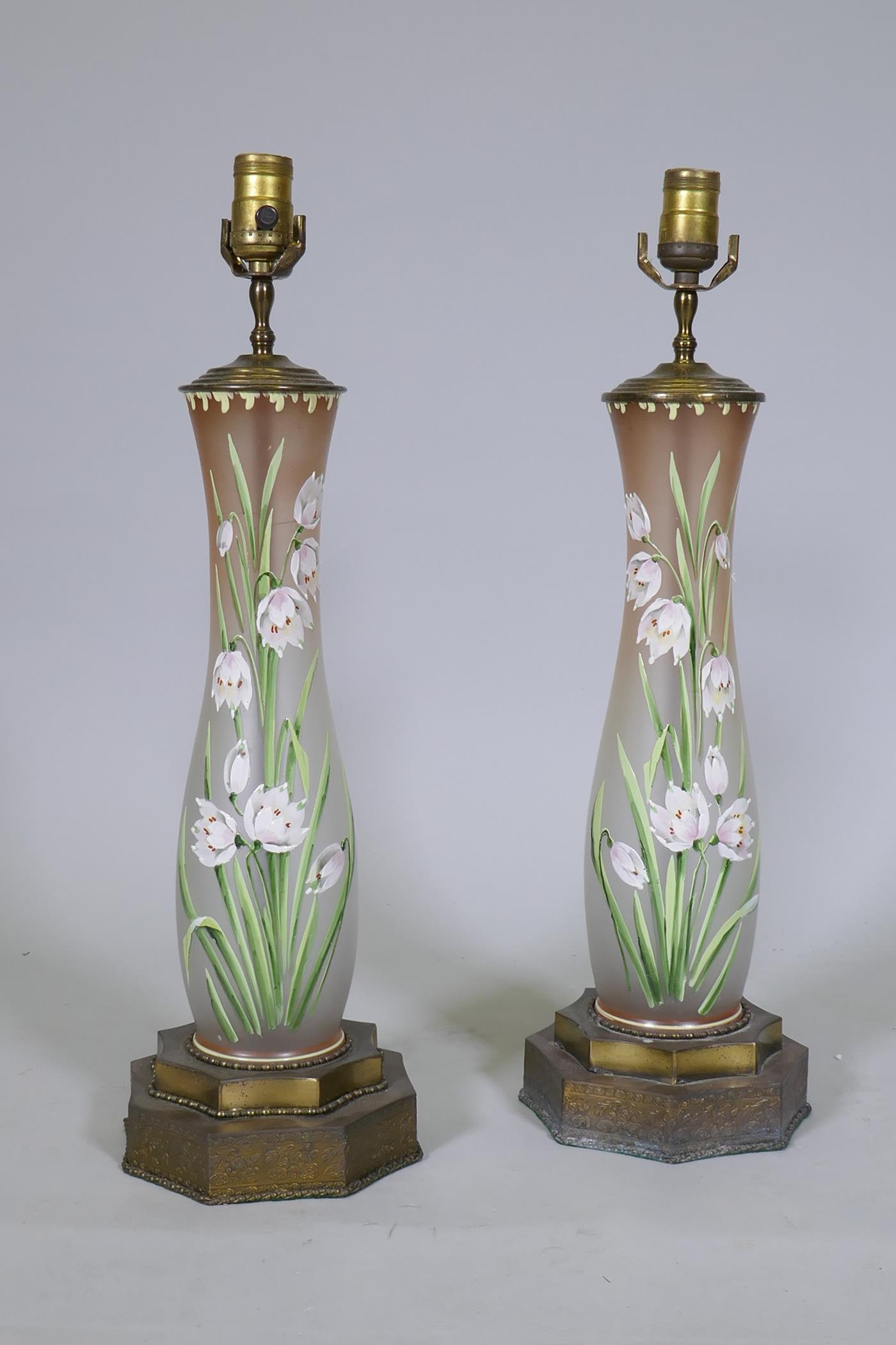 A pair of opaline glass table lamps with hand painted enamel decoration, raised on metal bases, 56cm
