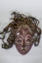 An African tribal carved and painted wood mask with braided straw decoration