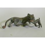 An Eastern bronze figure of a lion with prey, 20 x 7cm high