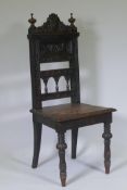 An antique oak hall chair with carved back and lion mask decoration, raised on carved turned