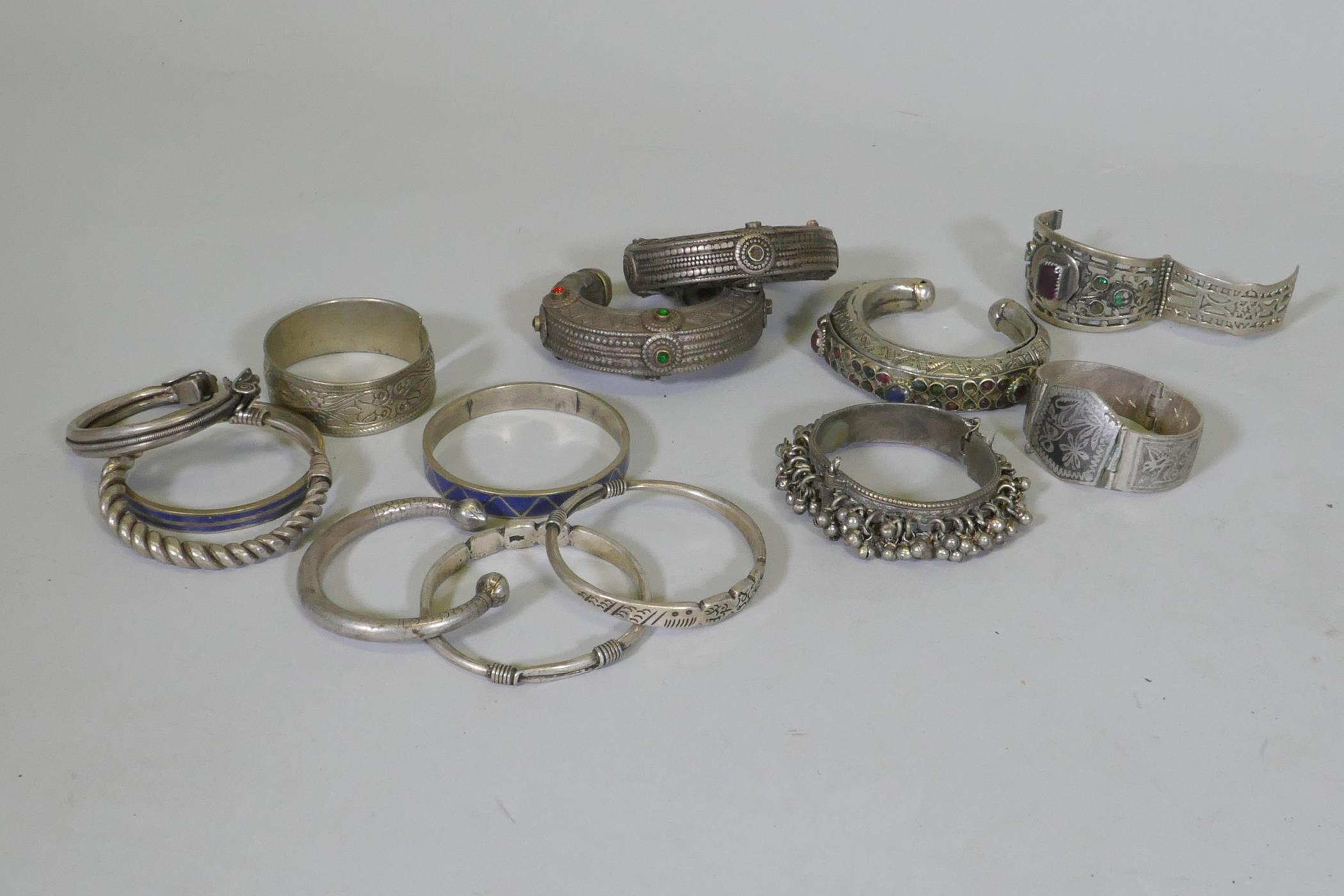 A collection of Afghan white metal bangles, set with paste stones, bidri style decoration, a Chinese