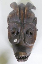 An African tribal carved wood horned mask with hinged jaw, 50cm long, AF minor loss and break