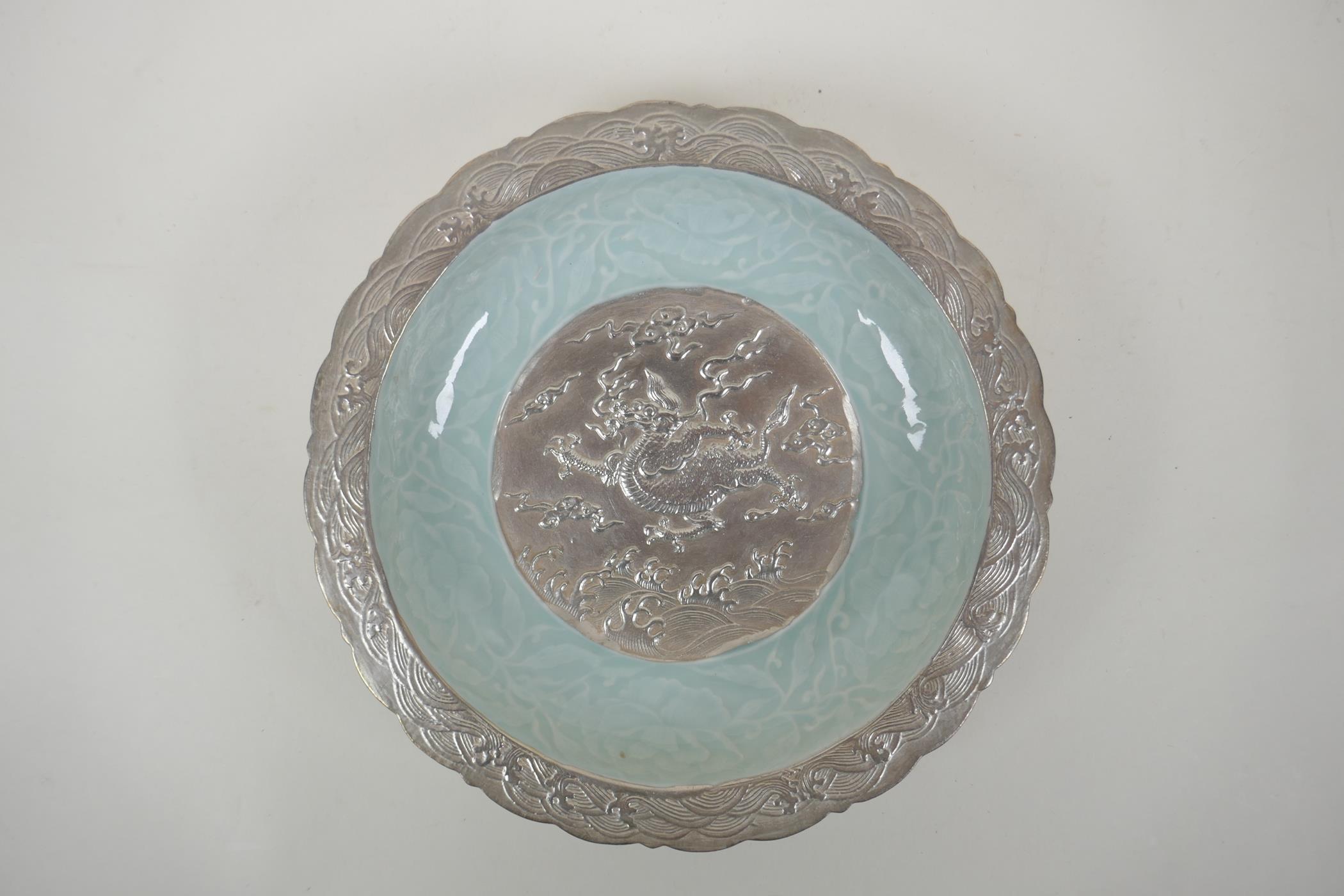 A Chinese celadon and silver glazed porcelain bowl with lobed rim, decorated with a dragon and lotus