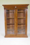 A C19th mahogany bookcase with moulded frieze over two glazed doors,