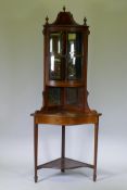 A Victorian mahogany corner display cabinet with single bow front glazed cupboard, mirror back and