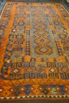 A large Middle Eastern orange and burgundy ground hand woven kilim carpet, 310 x 500cm