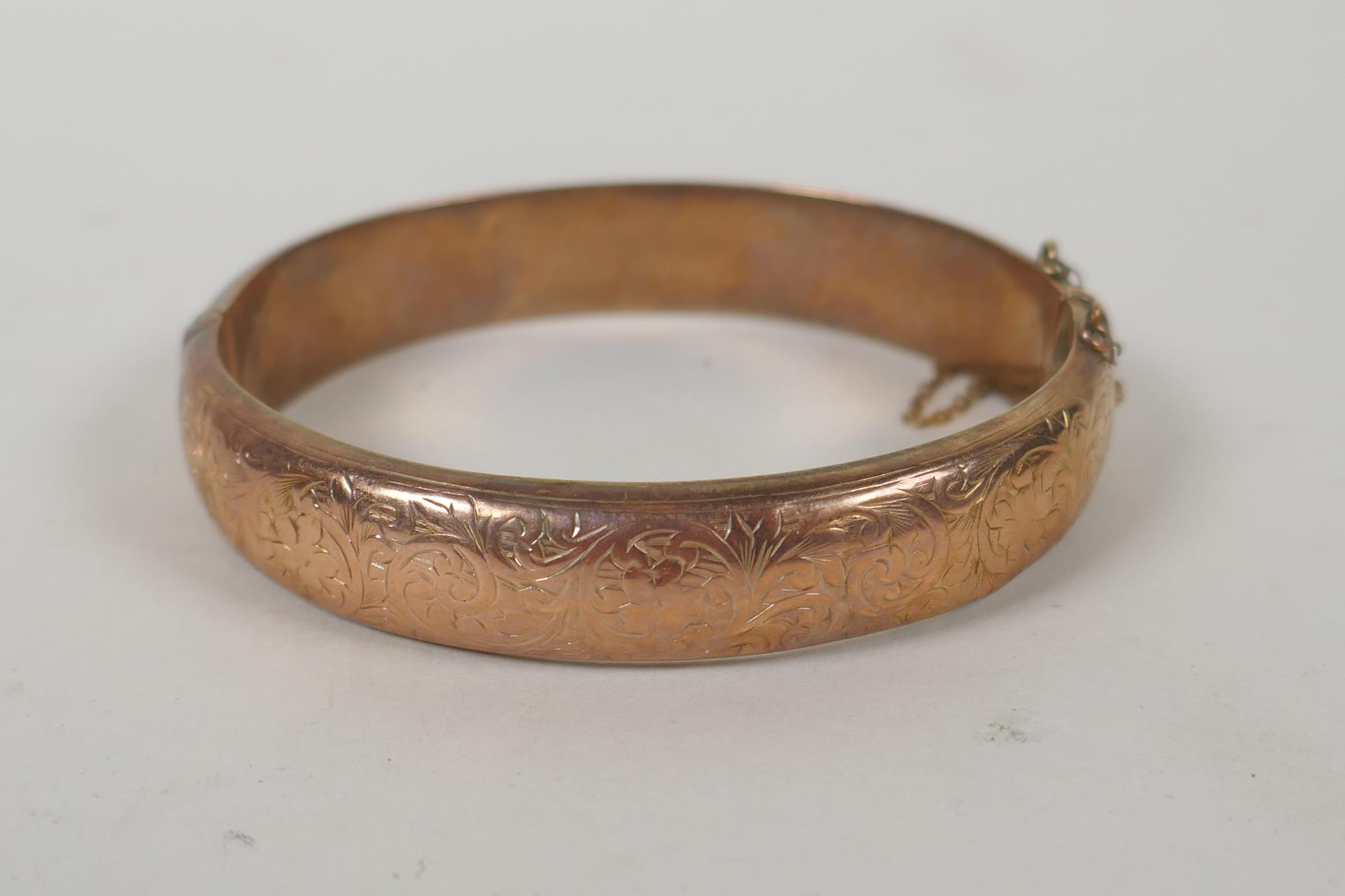 A 9ct gold bangle with scrolling decoration and inscription, 6 x 5.5cm, 14.9g