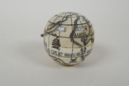 A nautical style carved bone compass and sundial in the form of a globe, 4cm diameter