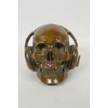 A decorative filled bronze skull wearing headphones, 16cm high