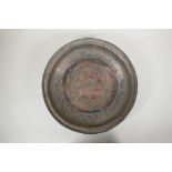 An antique Islamic copper dish with chased script and floral decoration, 34cm diameter