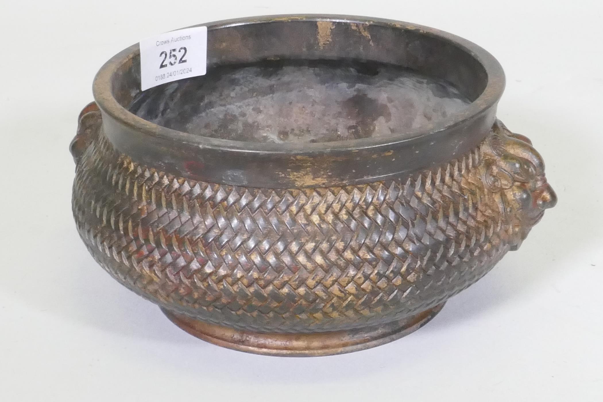 A Chinese bronze censer with mask decoration and woven basket style body, impressed seal mark to