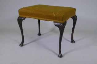 A Georgian style oak footstool, raised on cabriole supports with carved palm and harebell