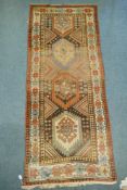 A multi colour ground Kurdish Kazak wool runner with a geometric medallion design on a brown