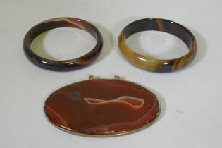A pair of agate bangles, 16.3cm internal diameter, and an agate pendant in metal mount